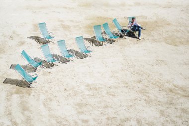 on deck chairs in the sand read a book clipart
