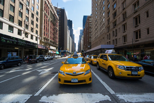 New York City, USA - August 3, 2013:the famous yellow taxis waiting patiently for pedestrians to pass through the skyscrapers of New York