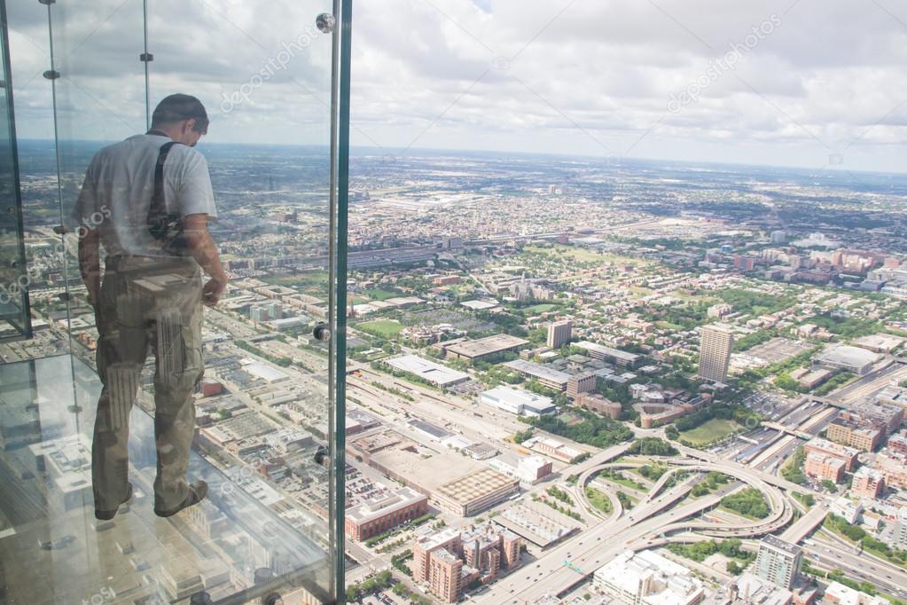 A boy looks out from the transparent balcony of th willis tower