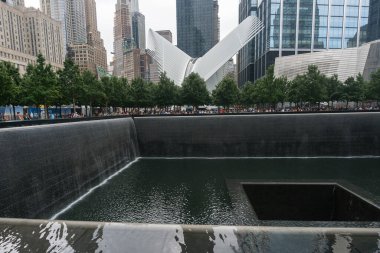 New York City, ABD - 7 Ağustos 2019: İnsanlar New York 'ta, Santiago Calatrava tarafından tasarlanan Oculus adlı metro istasyonunun ve Ground Zero Anıtı yakınlarındaki bulutlu bir günde geziniyorlar.