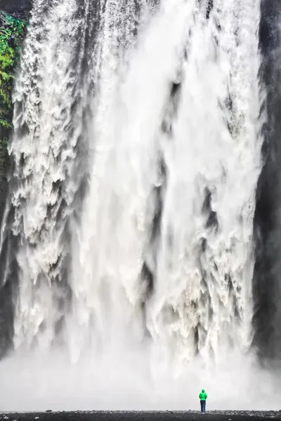 Mulher em pé na frente da gigantesca cachoeira Skogafoss na Islândia — Fotografia de Stock