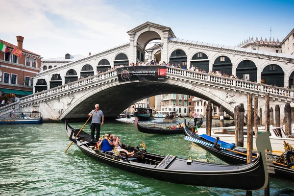 VENICE - JULY 11: Traditional gondolas and boats on Canal Grande at famous Rialto bridge on July 11, 2013 in Venice, Italy. The high traffic volume on Canal Grande is one of the city's major concerns. — Stock Photo, Image