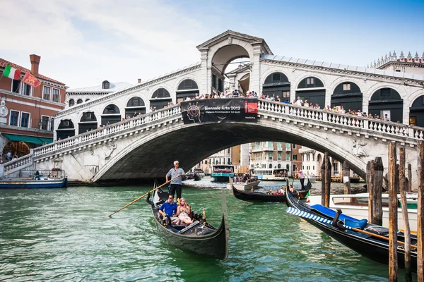 VENICE - JULY 11: Traditional gondolas and boats on Canal Grande at famous Rialto bridge on July 11, 2013 in Venice, Italy. The high traffic volume on Canal Grande is one of the city's major concerns. — Stock Photo, Image