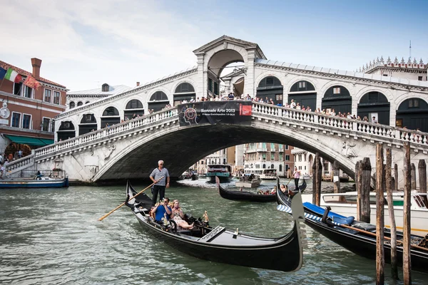 VENICE - JULY 11: Traditional gondolas and boats on Canal Grande at famous Rialto bridge on July 11, 2013 in Venice, Italy. The high traffic volume on Canal Grande is one of the city's major concerns. — Stock Photo, Image