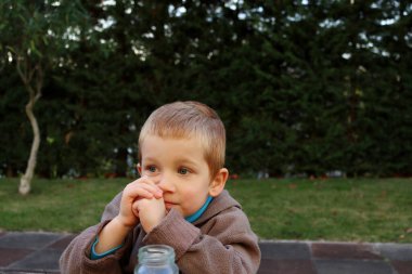 Sarışın çocuk mesafeye düşünceli bir şekilde bakıyor. Dört yaşında bir çocuk eliyle yanağını destekliyor.. 