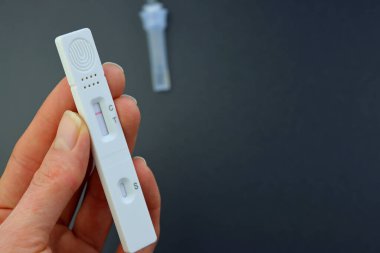 Covid-19 tükürük testi sonuçları negatif çıktı. Gri arka planda bir kadın eli var. 15 dakika içinde IgM / IgG antikorları ve bağışıklığı tespit etmek için test kiti