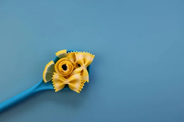 Žluté Těstoviny Farfalle Plátky Citrónová Kůra Modré Lžičce Modrém Pozadí — Stock fotografie