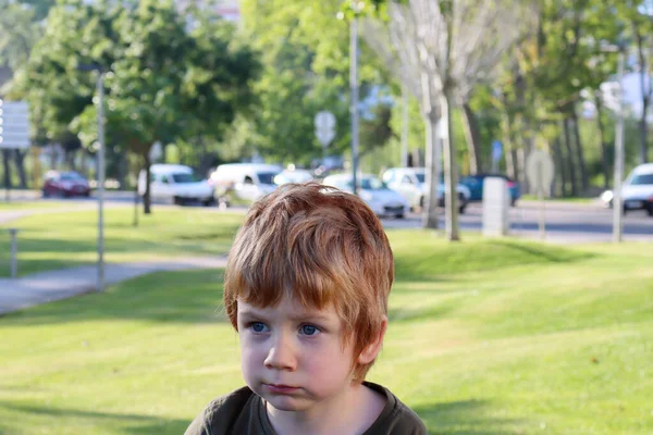 金髪の少年は遠くを見て微笑む ぼやけた緑の背景をした5歳の少年の肖像画 — ストック写真