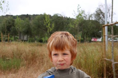 Sarışın çocuk gözlerini kıstı ve ağzını burktu. Beş yaşındaki çocuk yüzünü buruşturdu..