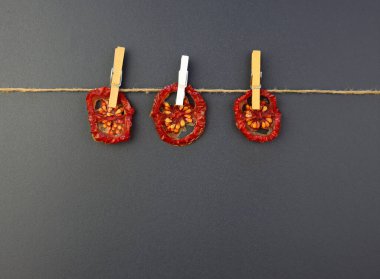 Kurutulmuş domatesler gri arka plandaki mandallara asılır. Evde kurutulmuş domates.