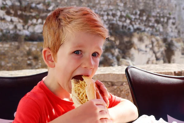 Blondyn Otwiera Usta Gryzie Wypchaną Bułkę Pięciolatek Jedzący Uliczne Żarcie — Zdjęcie stockowe
