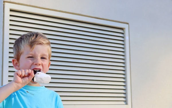 金髪の少年は目を細めてアイスクリームを舐めた 五歳の少年は悲しみを見せる — ストック写真