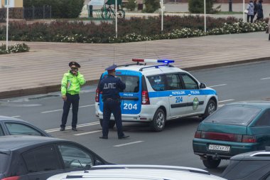 Uralsk, Kazakistan (Kazakistan), 22.09.2021 - iş sırasında telsizle iletişim kuran bir polis memuru, yolun ortasında devriye arabasının arkasında duruyor