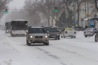 Uralsk, Kazakhstan (Qazaqstan), 11.03.2022 - Cars in the city in winter. Snowstorm and auto traffic in the city. Winter road. Urban bustle. Buses and cars on the road.