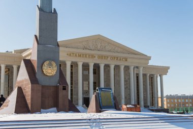 Uralsk, Kazakistan (Kazakistan), 12.03.2022 - Bağımsızlık Anıtı, devlet amblemi ve Nazarbayev Meydanı 'ndaki marş, arka planda Uralsk kentindeki Atameken sanat merkezi