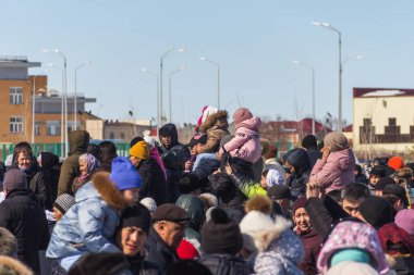 Uralsk, Kazakistan, 22.03.2022 - Bir konser izleyen bir kalabalık, ebeveynlerinin boynuna oturup bir konser izleyen çocuklar, Kazakistan 'da ulusal bahar tatili, tatil yapan bir kalabalık