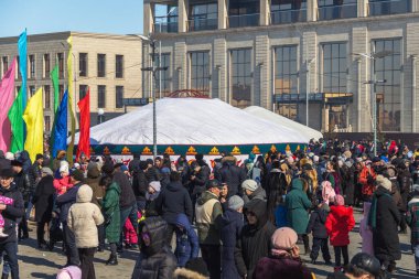 Uralsk, Kazakistan (Kazakistan), 22.03.2022 - Kazakistan 'da bahar tatili Nauryz, festivalde bir grup insan, arka planda Kazak yurdu ve renkli bayraklar