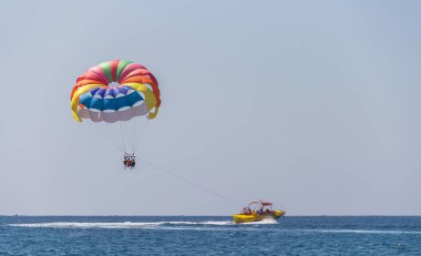 Türkiye, Alanya, Side, 27.08.2021: Olağanüstü eğlence, paraşütle atlayan turistler bottan halatla atlıyor, paraşütle denizin üzerinde uçuyor