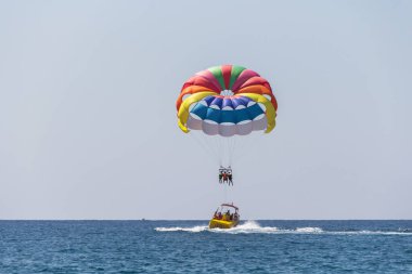 Türkiye, Alanya, Side, 27.08.2021: Olağanüstü eğlence, paraşütle atlayan turistler bottan halatla atlıyor, paraşütle denizin üzerinde uçuyor