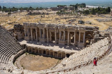 Türkiye, Denizli, 29.08.2021: Hierapolis, Türkiye 'deki Roma antik amfitiyatrosu. Kırmızı elbiseli ve şapkalı bir kız antik bir tiyatronun arka planında fotoğraflanıyor. Türkiye 'de Seyahat.