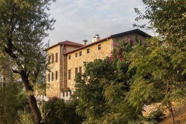 Türkiye, Alanya, 30.08.2021: Türkiye 'de bir dağın tepesinde taştan yapılmış bir ev, pitoresk bir yerde bir ev, bir dağın yamaçlarında ağaçların arasında bir ev