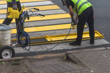 Uralsk, Kazakhstan (Qazaqstan), 13.07.2022 - Workers are marking the pedestrian crossing with yellow paint. Pedestrian crossing marking