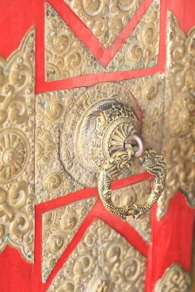 Richly carved brass knob on red painted door. — Stock Photo, Image