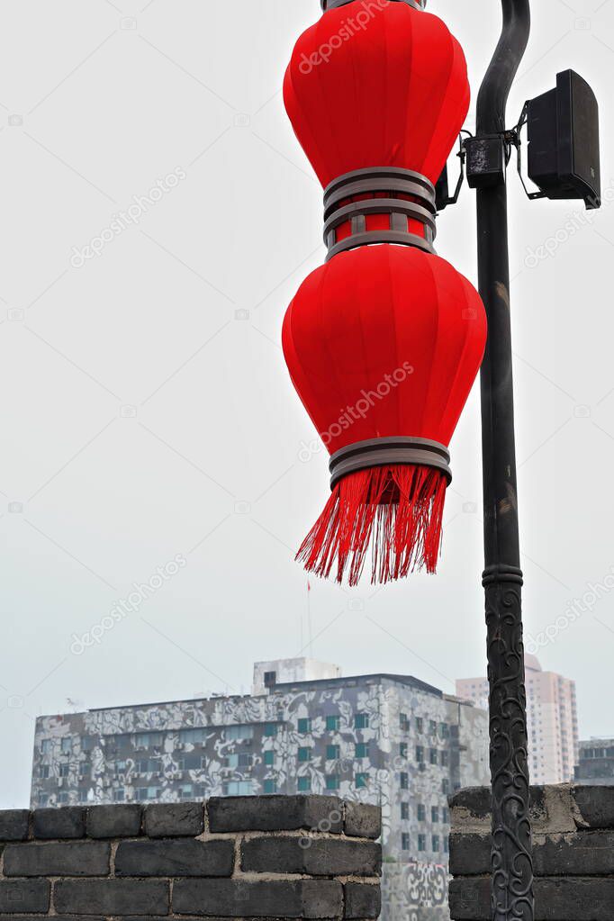 Chinese style red lantern-loudspeaker for ambient music and messages to visitors-foggy smoggy sky-modern building background-City Wall's Wenchang Prosperity of Learning Gate area. Xi'an-Shaanxi-China.