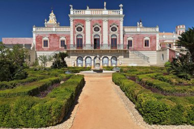 NeoRococo sarayının bahçesine bakan pembe ön cephe. Çakıl yollu çitler, çeşme merkezli balkon, pencereler, çatı pencereleri, balataları üzerinde heykeller. Estoi Bölgesi-Faro-Algarve-Portekiz