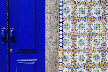 Ön cephe detayı - Neoklasik konak, koyu mavi kapılı, sade kapı levhası Portekiz azulejo 'sunun kare parçalı, çiçekli ve geometrik motiflerle kaplanmış duvarını gösteriyor. Tavira-Algarve-Portekiz.