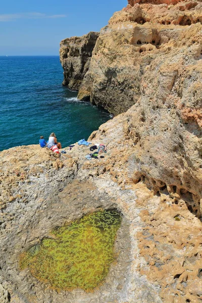 INCIDENTAL PEOPLE-Tidal pool carved out by sea waves in the natural monument of Algar Seco-series of rocks and rugged caves sculpted on the rocky coast east of Carvoeiro town. Lagoa-Algarve-Portugal.