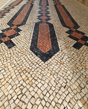 Portekiz kaldırımı ya da Calcada Portuguesa küçük beyaz-kırmızı-siyah taş parçaları mozaik şekilli düzenlenmiş veya yaya Rua Infante de Sagres caddesinde görüntü. Lagos-Algarve-Portekiz.
