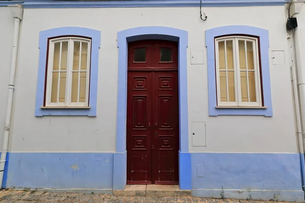 白色的正面是一楼的旧新古典主义建筑 有栗色木门和节段拱门 窗户上有百叶窗 底板和边框是紫色的 拉各斯 阿尔加夫 葡萄牙 — 图库照片