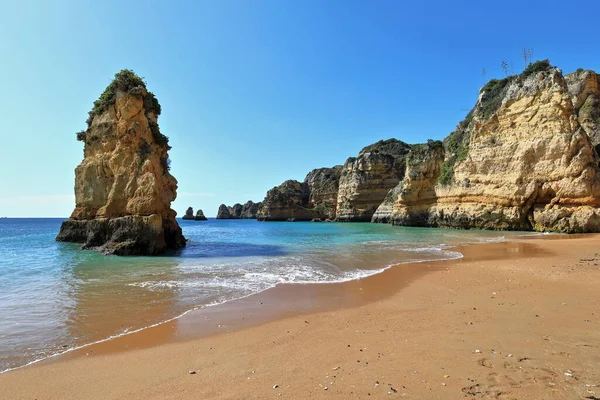 Praia de Dona Ana Sahili 'ndeki deniz yığını kaya oluşumu, kumlu bölgenin arka planını oluşturan altın kireçtaşı ve kırmızı kil kayalıkların en güney ucunda. Lagos-Algarve-Portekiz.