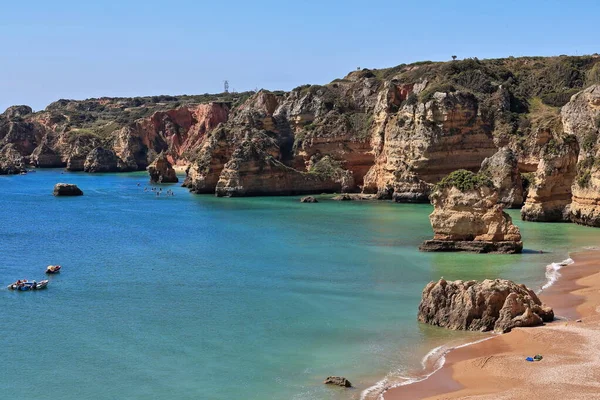 Praia de Dona Ana Sahili 'ndeki deniz yığını kaya oluşumu, kumlu bölgenin arka planını oluşturan altın kireçtaşı ve kırmızı kil kayalıkların en güney ucunda. Lagos-Algarve-Portekiz.
