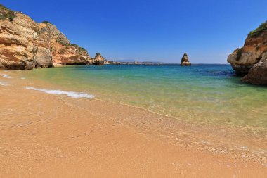 Erotik kayalıklar ve kumtaşı kireçtaşı yığınları Praia 'nın güney ve kuzey kesimlerinde yüzerken kıyıdan geçen deniz kanoları ve Camilo Sahili turist motorları. Lagos-Algarve-Portekiz.
