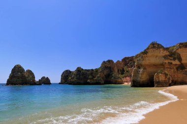 Praia 'dan güneye doğru Camilo Sahili' nin kuzeyinden sağa doğru kayalıklar güneyde ve sahilin güney bölümünün en güney ucundaki deniz yığınlarını kapatıyor. Lagos-Algarve-Portekiz.