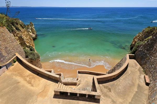 Long staircase with a series of terraces built into the cliff leading down to the northern and smaller part that gets fully water-covered at high tide of Praia do Pinhao Beach. Lagos-Algarve-Portugal.