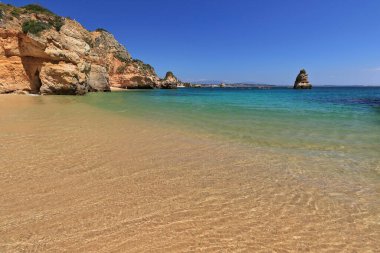 Erotik kayalıklar ve kumtaşı kireçtaşı yığınları Praia 'nın güney ve kuzey kesimlerinde yüzerken kıyıdan geçen deniz kanoları ve Camilo Sahili turist motorları. Lagos-Algarve-Portekiz.