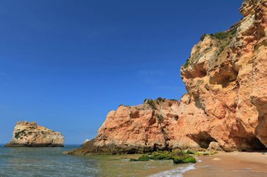 Praia da Prainha Sahili 'nin orta kesimindeki deniz yığınları ve uçurumların dibinde deniz dalgaları tarafından oyulmuş doğal mağaralar ve delikler. Alvor Portimao-Algarve-Portekiz.