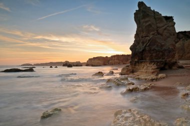 Praia do Amado Sahili üzerinde gün batımını gösteren uzun bir sergi doğudan batıya, alacakaranlık manzaralı Ponta de Joao d 'Arens' e çekildi. Portimao-Algarve-Portekiz.