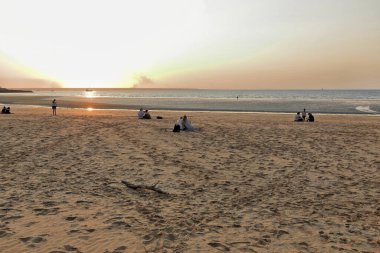Sunset over Mindil Beach at low tide located in The Gardens suburb facing northwest on Fannie Bay-incidental people in the image. Darwin-Northern Territory-Australia.