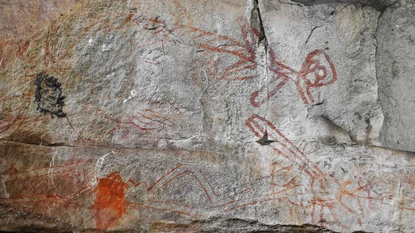 Ancestral Aboriginal rock art: faded paintings of unidentified beings-animals-spirits or objects outlined in red pigment on the stone wall of a rocky shelter. Ubirr site-Kakadu NP-NT-Australia.