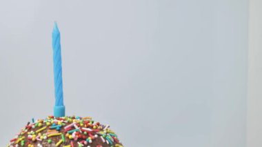 Doğum günü, pastel mavi arka planda yanan renkli mum. yavaş çekim