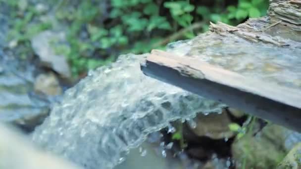 Una corriente de agua de montaña limpia y transparente que fluye por una alcantarilla de madera de cerca — Vídeo de stock