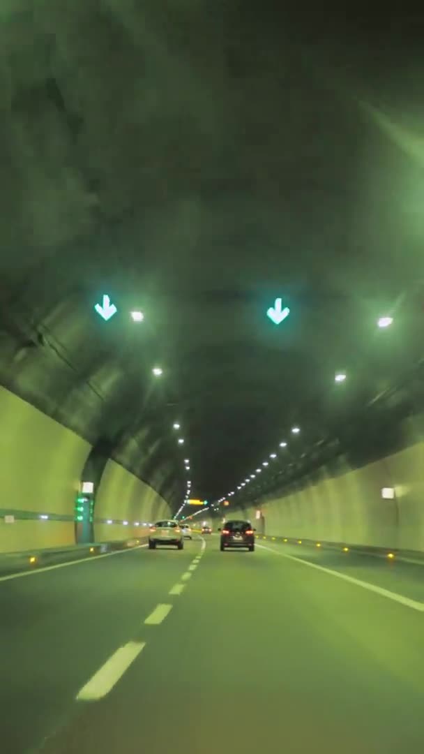 Coches borrosos que conducen a través de un túnel de montaña en Italia. Tráfico con líneas brillantes de alta velocidad. paisaje natural, vídeo vertical — Vídeo de stock