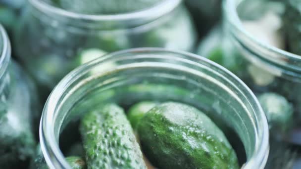 Cucumbers in jars are returned to the table, top view . close up — Stock Video