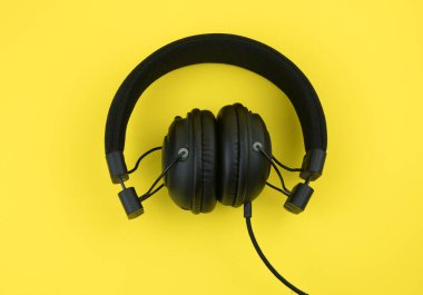Sarı arka planda siyah kablo kulaklıklar. Genel giderler, DJ ve müzisyenler için izole edilmiş profesyonel kulaklıklar.