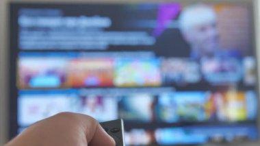 Akıllı bir televizyon için uzaktan kumanda kullanan bir erkek. Tv ekranı odaklı değilken kilitlenmiş görüntü
