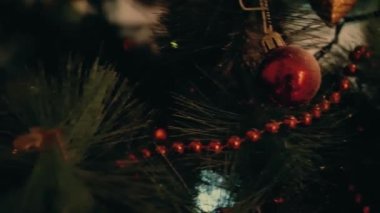 Birkaç kırmızı plastik Noel topları Noel köknar Yapay ağaç üzerinde asılı closeup. Yalpa tilt kadeh kırmızı Noel ağacı topları kapalı ile yapay yeşil Noel ağacı kadar.